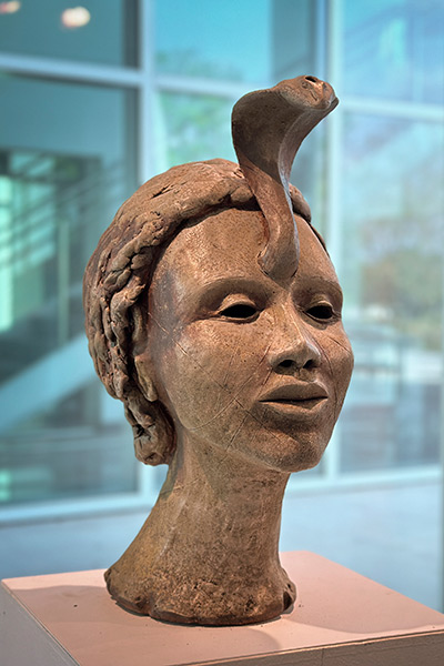 Sculpture of head with snake emerging from forehead