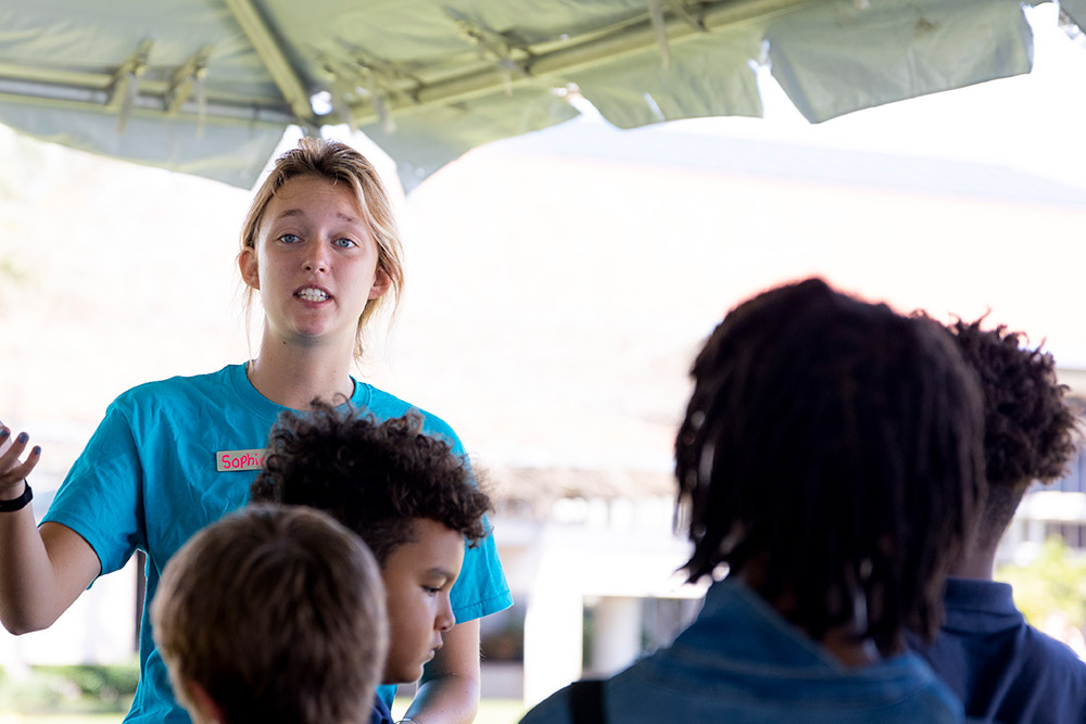 College student speaking to school children