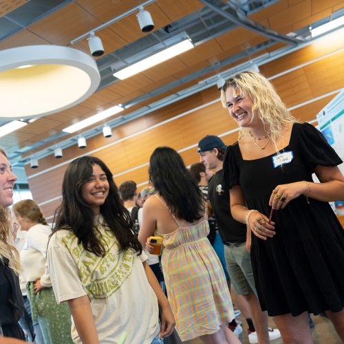 Group of students standing in front of student talking about a poster on an easel