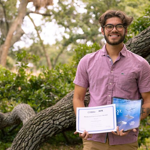 Student holding certificates and copy of magazine