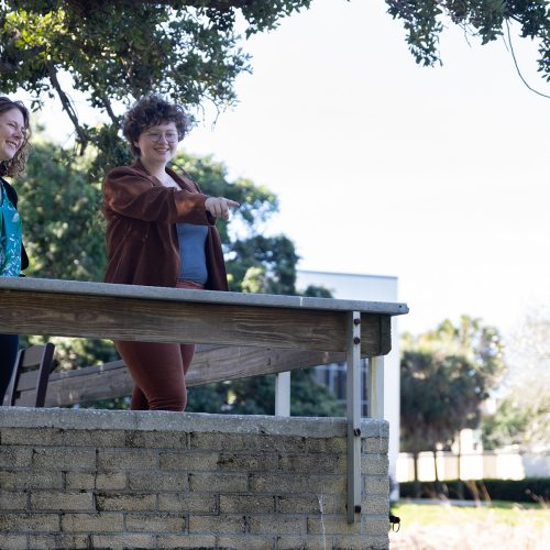 Professor and student look over side of wall by a pond