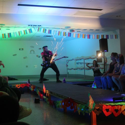 Student in drag plays guitar as sparks fly on stage