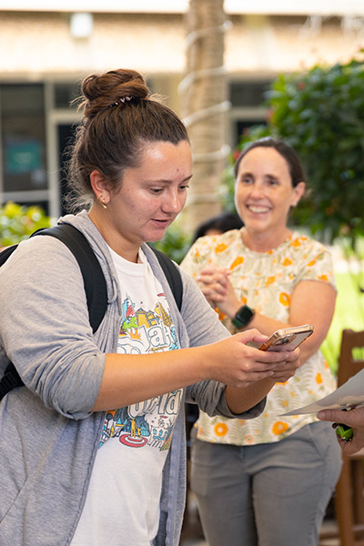 Student wearing backpack looks at mobile phone app