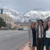 Three students stand on street with mountains in background