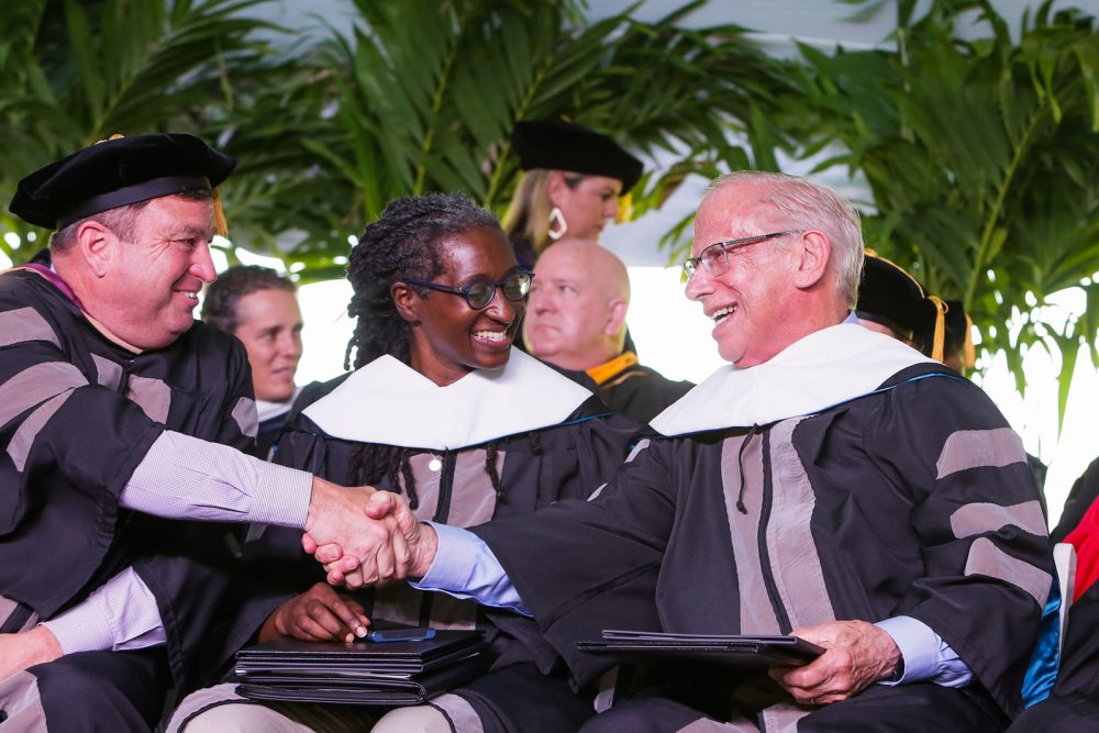 Two men in gowns shake hands