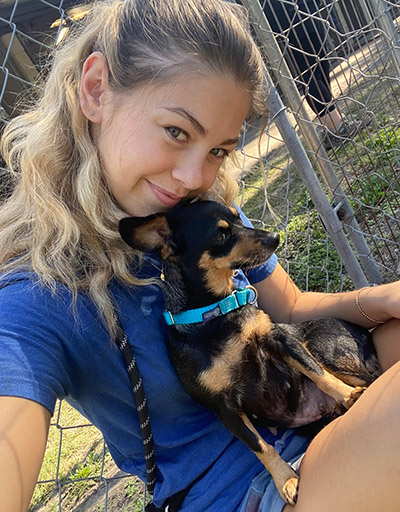 Student seated with small dog in lap