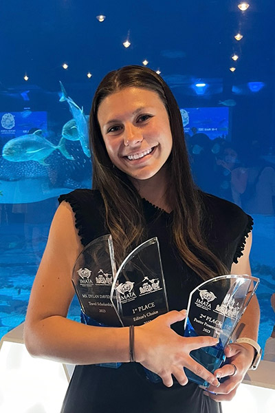 Student in front of aquarium holding trophies