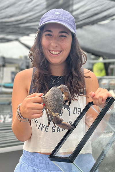 Student wearing hat and holding crab