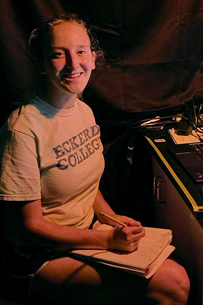 Student taking notes outdoors at night by red light