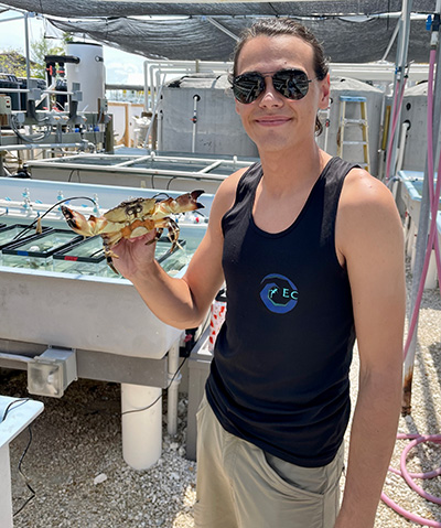 Student outdoors in sunglasses holding a crab