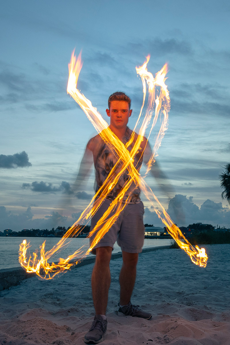 Eckerd College student swinging two fire torches