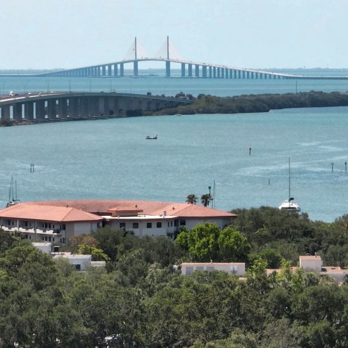 Aerial view of residence hall along the water with large bridge in the distance