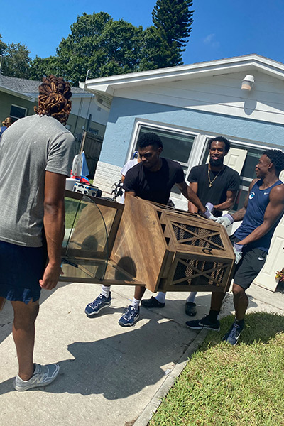 Four students moving damaged furniture to the curb