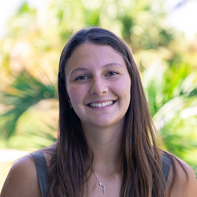 Student smiling with palm trees in background