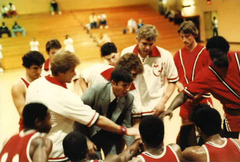 Coach in tie with players in a huddle around him