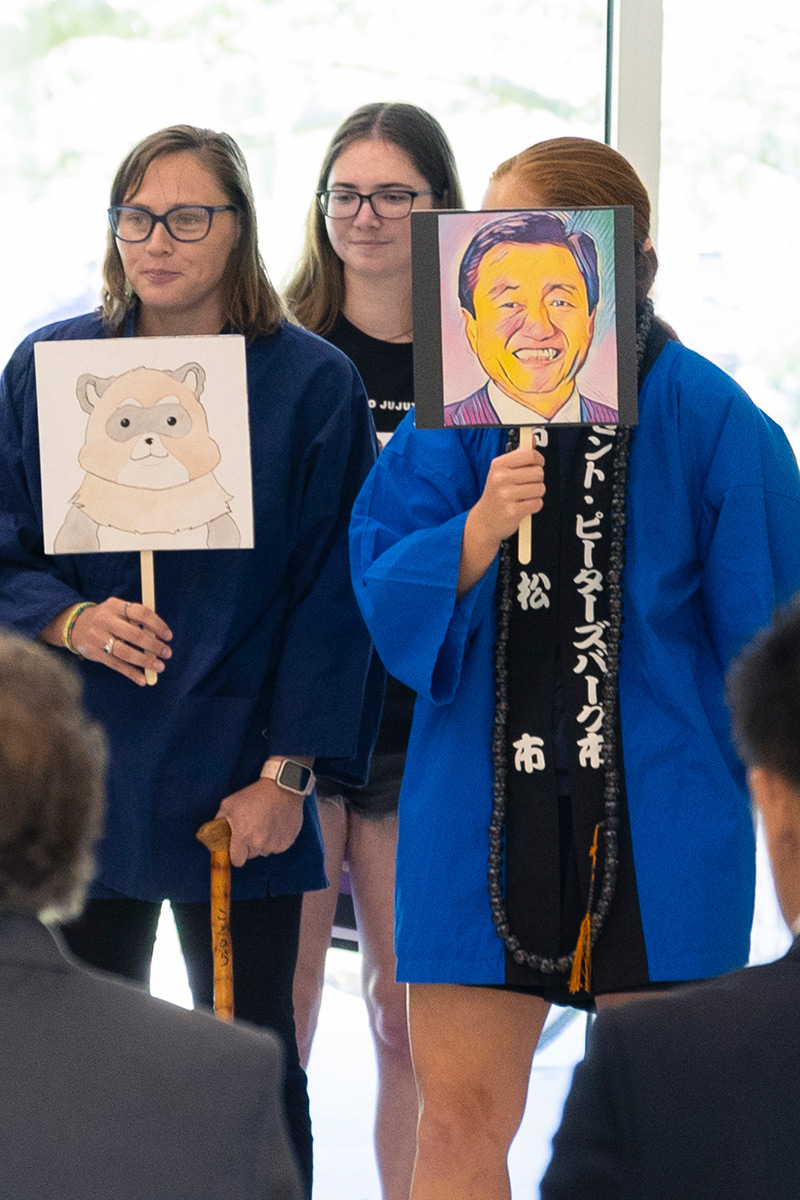 Students holding fans with illustrations of raccoon and mayor