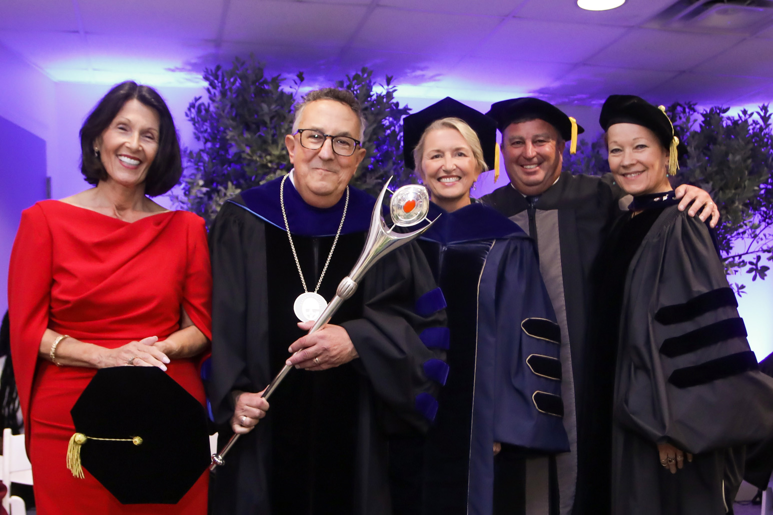 Annarelli holds mace on stage alongside his wife, two trustees and faculty member dressed in regalia