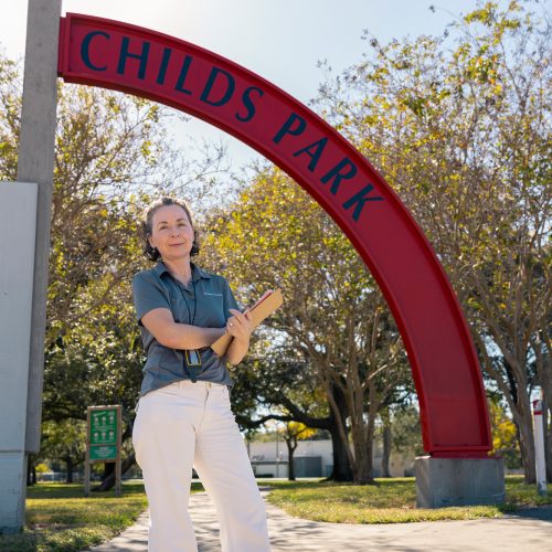 Professor standing with clipboard under a sign that says CHILDS PARK