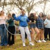 A group of students pass a hula loop while holding arms on a quad