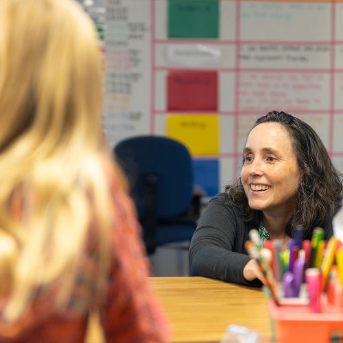 Professor sits at a low table with an elementary school student