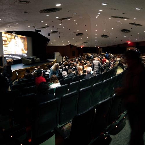 Wide angle view of stage and attendees inside a large auditorium