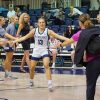 Eckerd College women's basketball player walks on to the court while shaking hands with girls