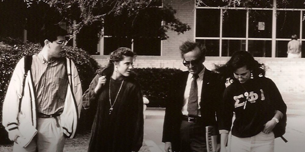 Students walk across campus with Wiesel in suit and tie