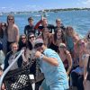 Large group of students on a boat heading away from shore