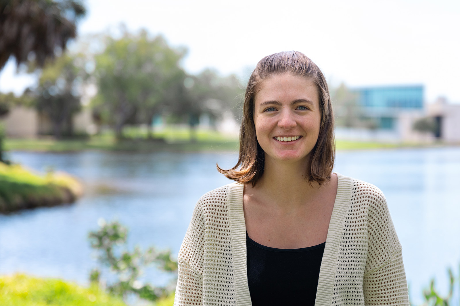 Student stands in front of pond in Florida setting