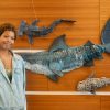 Student stands next to shark artwork hanging on the wall