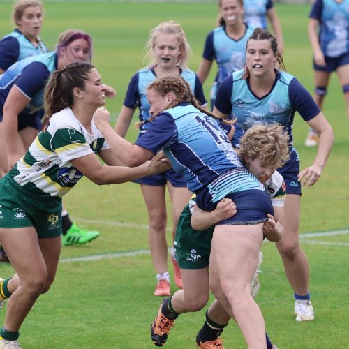 A rugby player getting tackled by two opposing team players