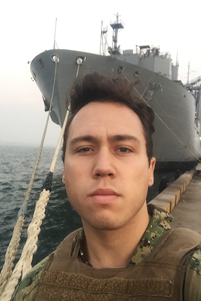 Young man in gear with large ship in background
