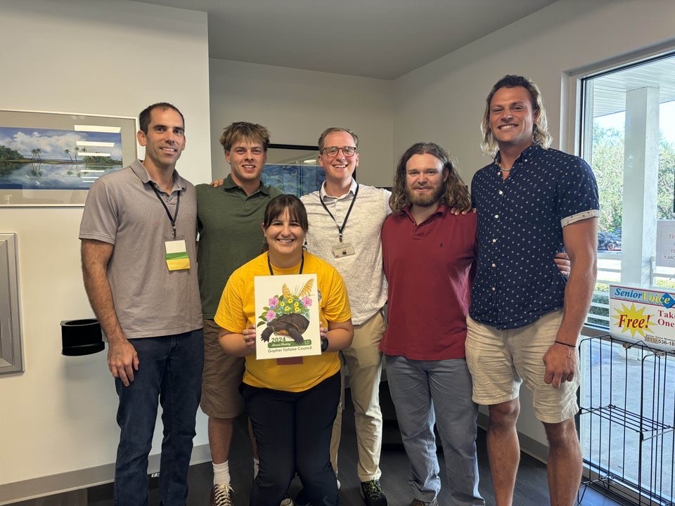Group of six people standing around a picture of a turtle