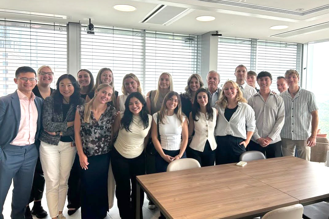 Group of students and professor in formal attire standing in business office