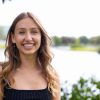 Student stands outside in front of pond