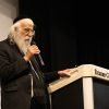 Man with long white beard wearing kippah speaks into microphone next to podium with text Eckerd College