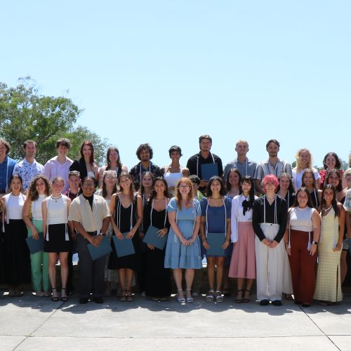 Large group of students, staff and faculty standing on outdoor patio