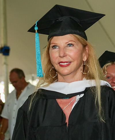 Woman in cap and gown walks down aisle