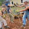 Student volunteers use shovels to remove red clay from the land
