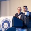 Man at podium that reads Eckerd College lifts award to show crowd