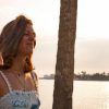 Student smiling by the water's edge as sun sets behind her