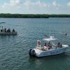Side view of two boats in the water after extending a long line that forms a large circle in the water
