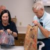 Man and woman open up bags of food onto a table