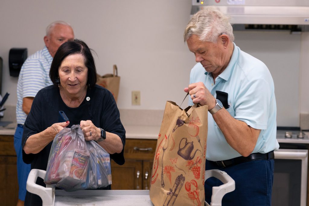 Man and woman open up bags of food onto a table