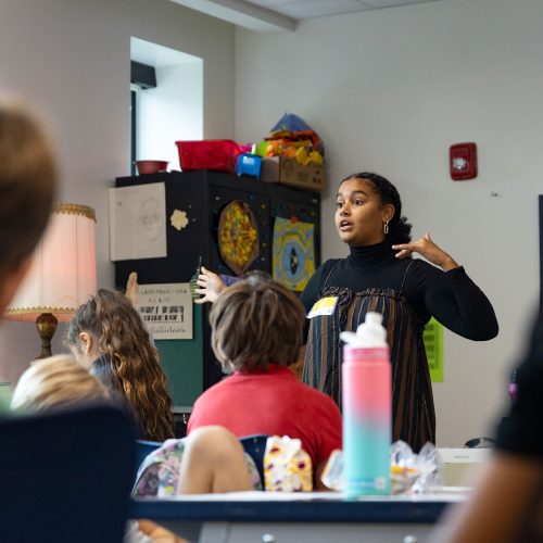 Eckerd student stands in a classroom before elementary school children