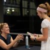 Author seated at table smiling at a student holding book