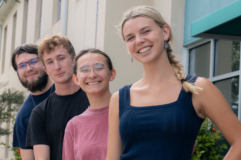 Logan Dudney '24, Zach Loreant '25, Nicole Szelistowski '24 and Sarah Campbell '23 pose in front of the USF marine science building.