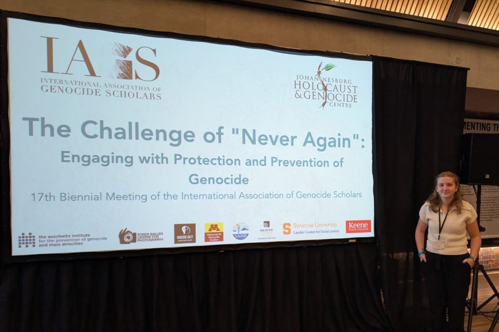 Hanna Kobs '26 stands next to a presentation display screen.