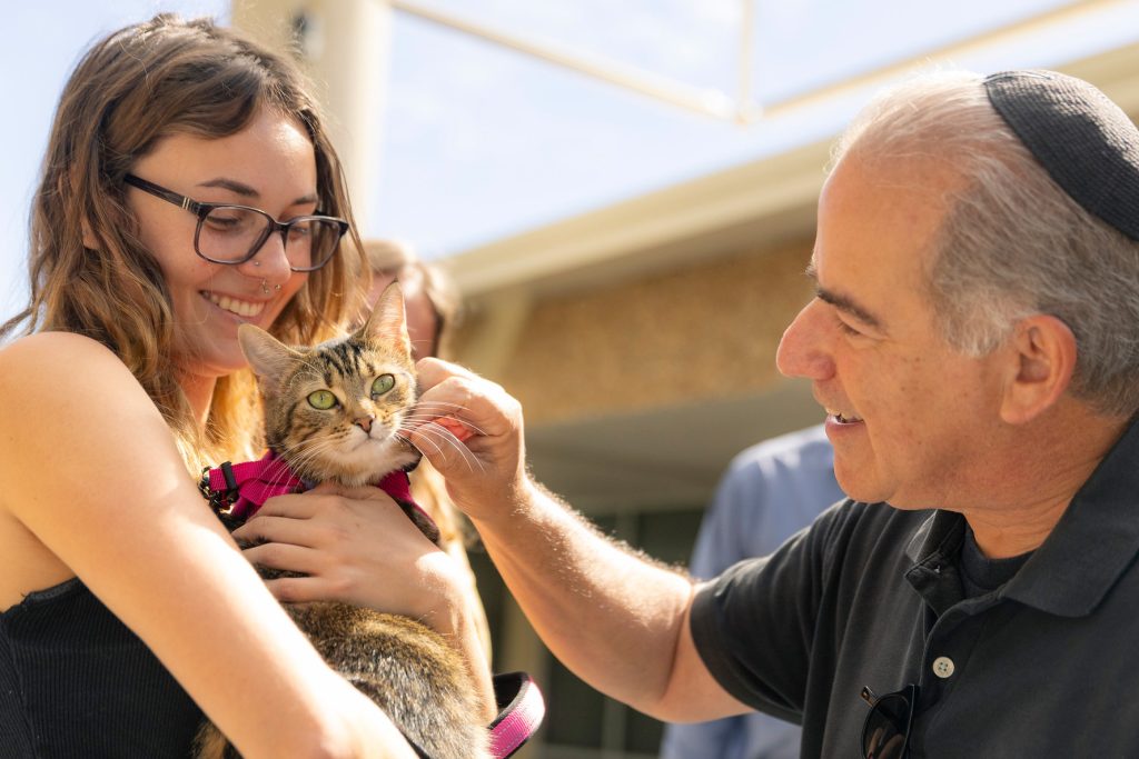 Rabbi caresses the cheek of a cat held by a student