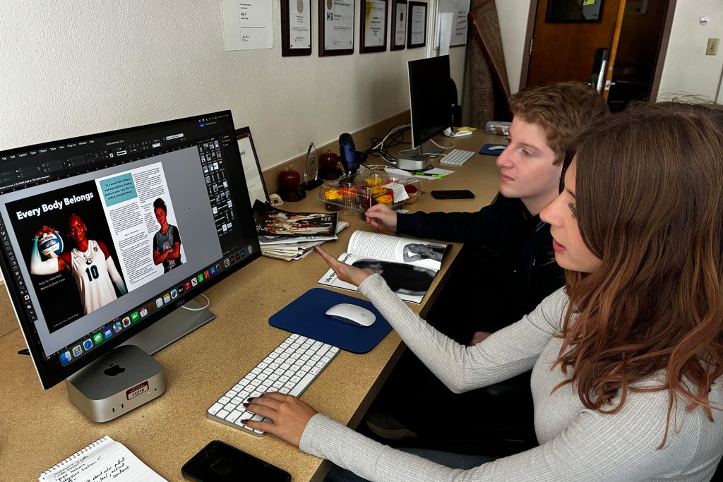 Two students sit next to each other before a computer screen with a layout showing an athlete with the heading EVERY BODY BELONGS